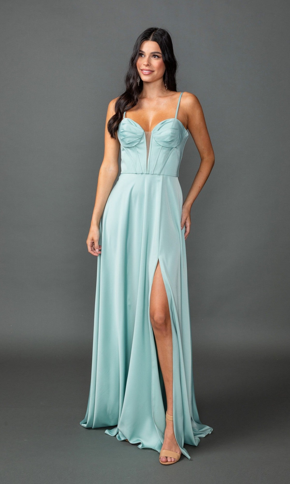 A woman stands against a plain gray background wearing the Dancing Queen 4544, a light blue long prom dress featuring an a-line silhouette, spaghetti straps, sweetheart neckline, and high slit.